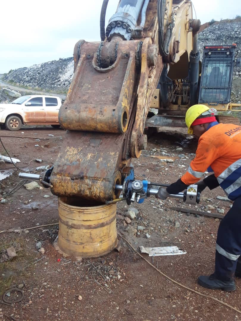 56429215-IMG-20221211-WA0004 Worker performing onsite repairs on a large excavator bucket using hydraulic tools, showcasing engineering solutions for mining operations.