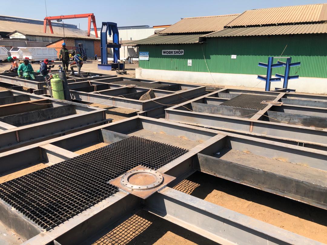 IMG-20240607-WA0015 Steel framework under construction at an industrial workshop, with workers engaged in welding and fabrication, supporting engineering solutions for mining.